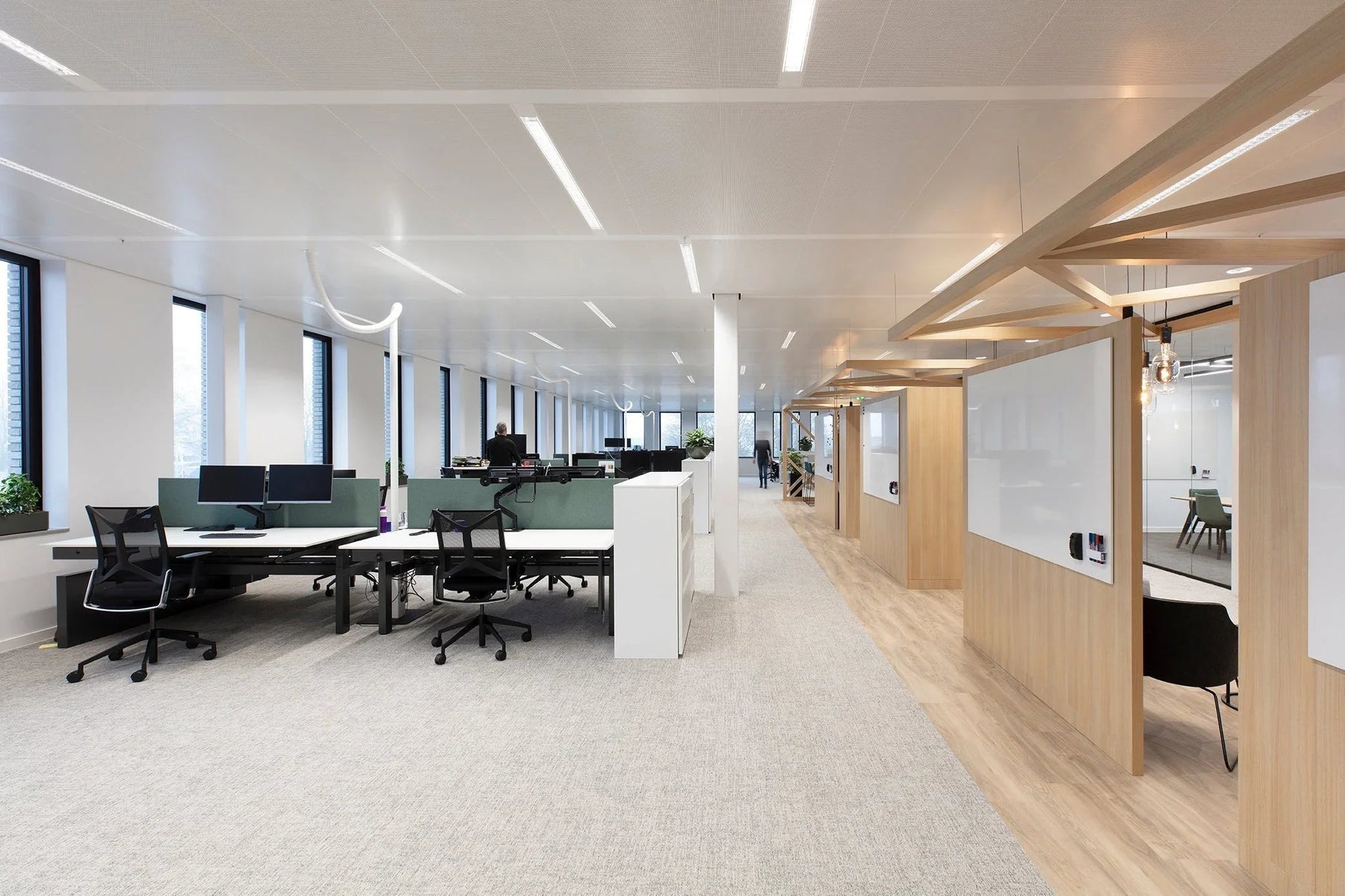 Modern kantoorruimte met design kantoormeubelen, bureaustoelen en werkplekken, veel glas en hout.
