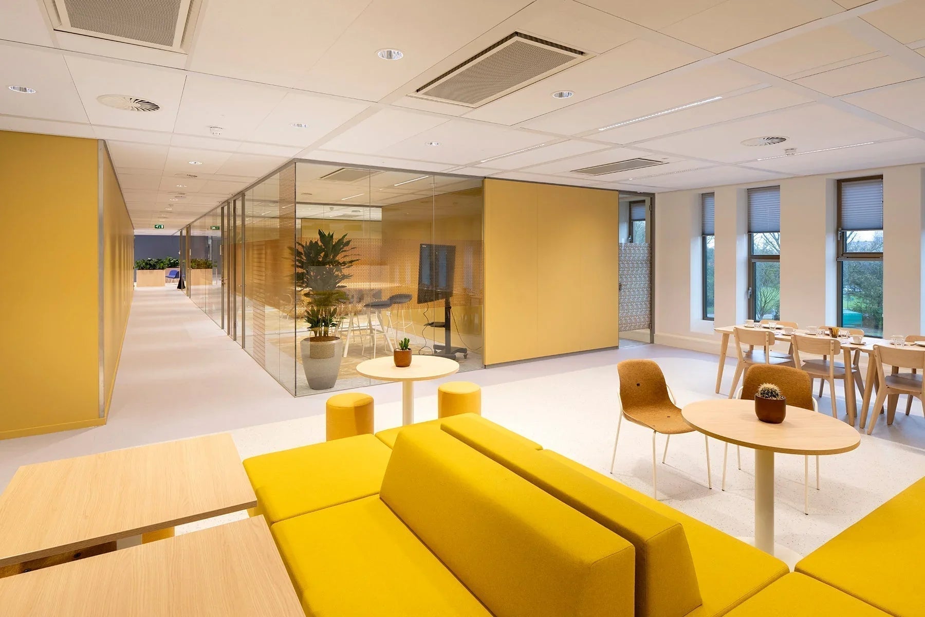 Modern kantoorinterieur met gele banken, glazen vergaderruimte en design kantoormeubilair.