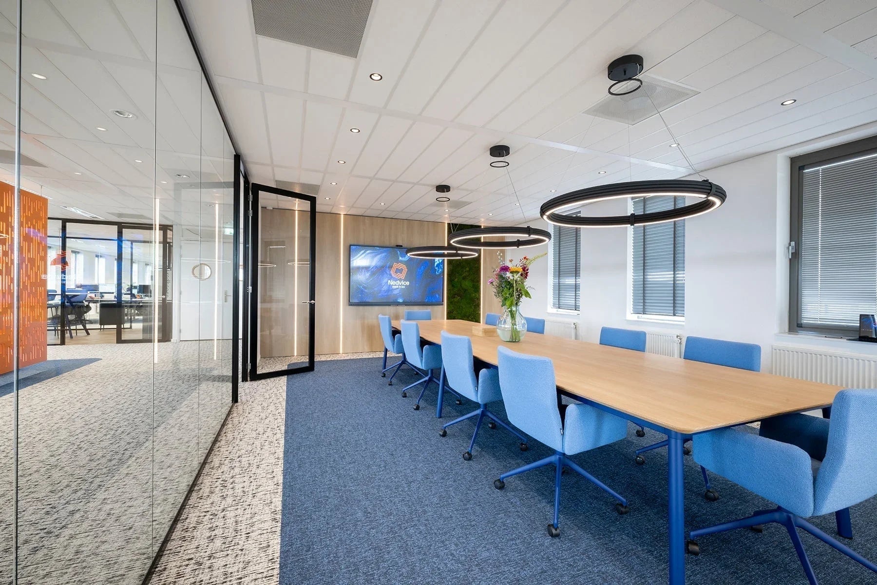 Moderne vergaderruimte met design kantoormeubilair, blauwe bureaustoelen en houten tafel.