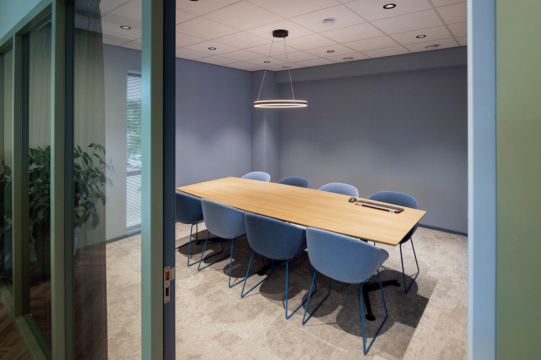Moderne vergaderruimte met design kantoormeubilair, houten tafel en blauwe stoelen
