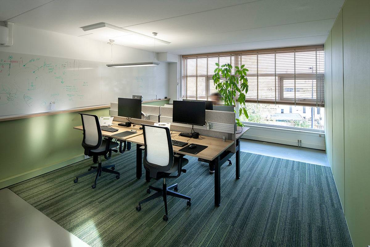 Modern kantoor met design kantoormeubels, bureaustoelen en werkplekken bij groot raam.