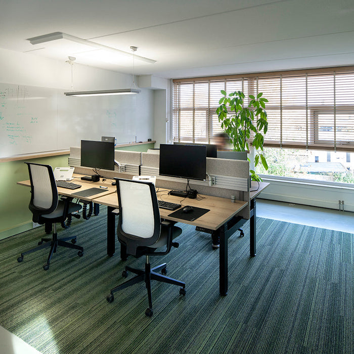 Modern kantoor met design kantoormeubels, bureaustoelen en werkplekken bij groot raam.