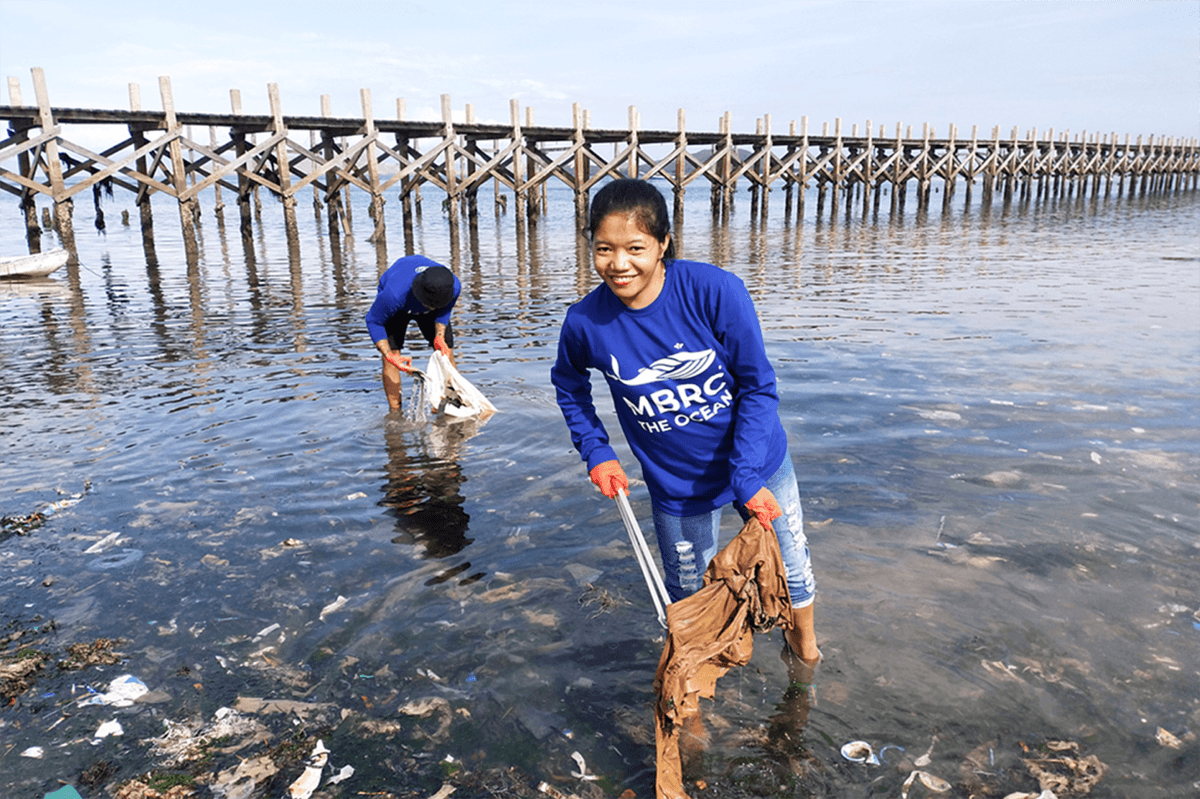 Vrouw en man ruimen afval op bij oceaan, milieuvriendelijke actie aan het water