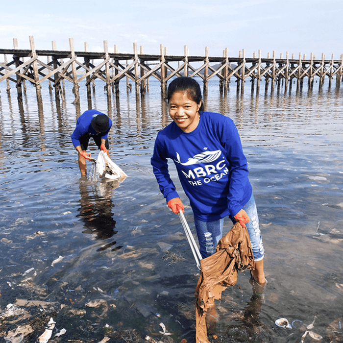 Vrouw en man ruimen afval op bij oceaan, milieuvriendelijke actie aan het water
