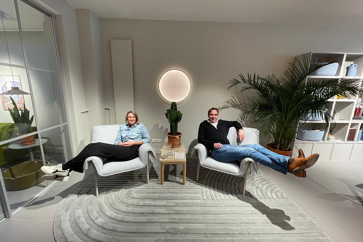 Twee personen ontspannen op moderne design fauteuils in een stijlvol kantoorinterieur met planten