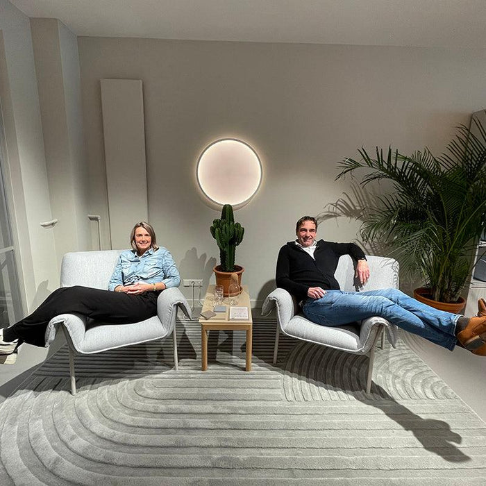 Twee personen ontspannen op moderne design fauteuils in een stijlvol kantoorinterieur met planten