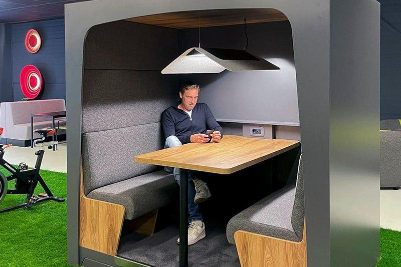 Stijlvol design kantoormeubilair met akoestische werkplek, man zittend aan houten tafel