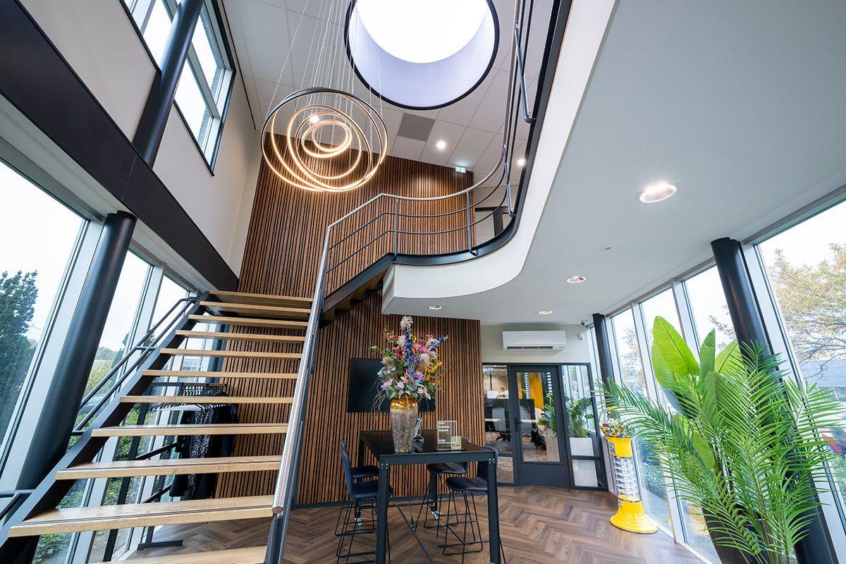 Modern kantoorinterieur met design kantoormeubels, houten trap en grote ramen.