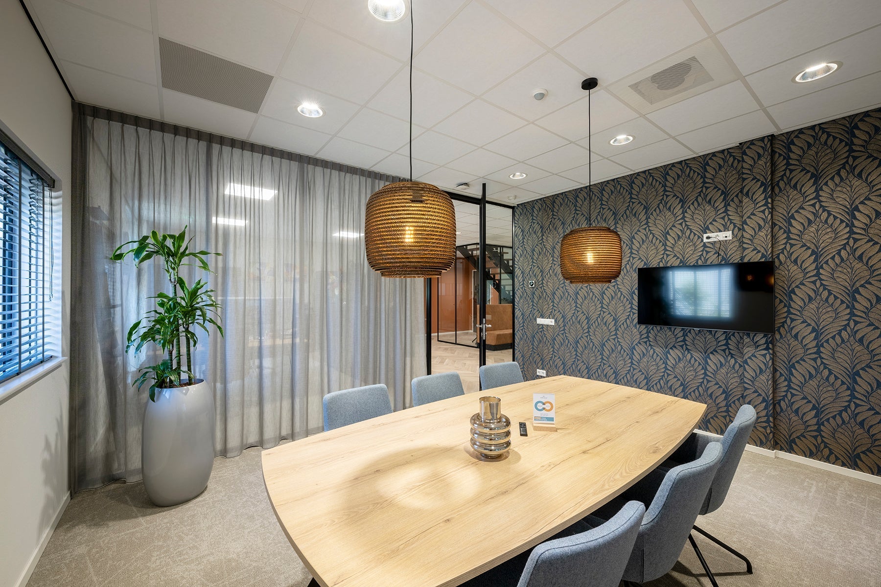 Moderne vergaderruimte met design tafel, blauwe stoelen, planten en akoestische kantooroplossingen