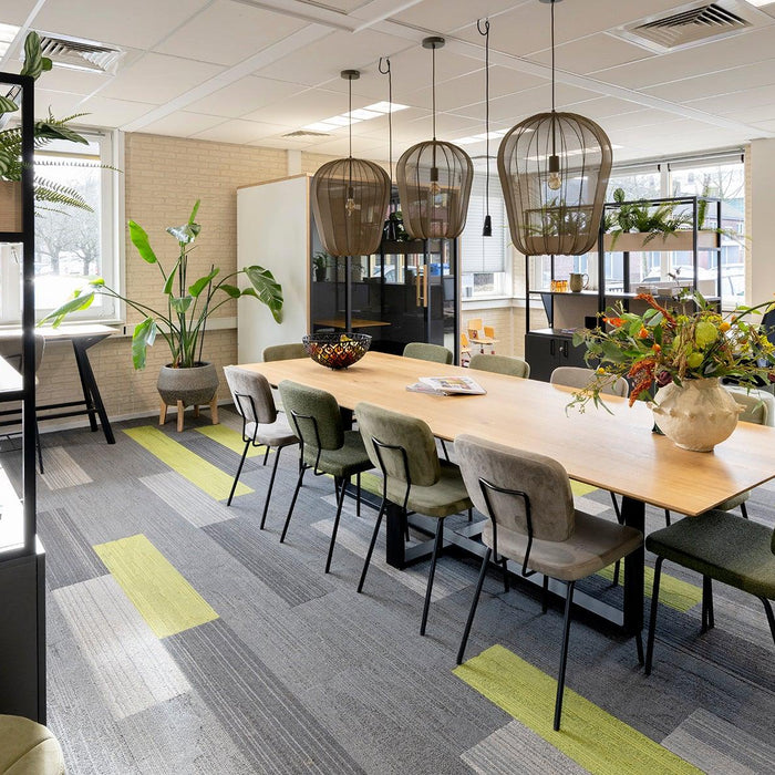 Moderne vergaderruimte met design kantoormeubilair, grote houten tafel en groene accenten.