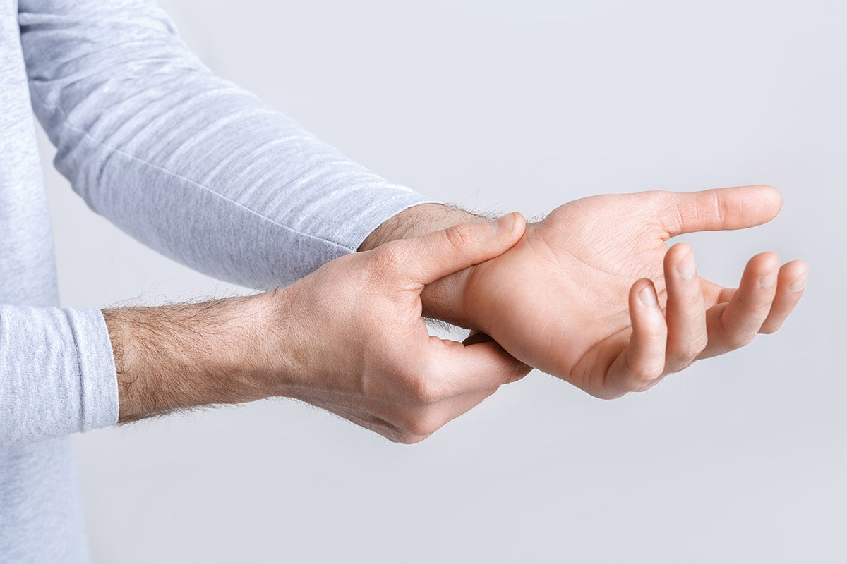 Man houdt zijn pols vast, mogelijk door pijn, ergonomische kantoormeubels advies