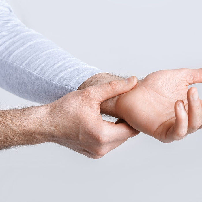 Man houdt zijn pols vast, mogelijk door pijn, ergonomische kantoormeubels advies