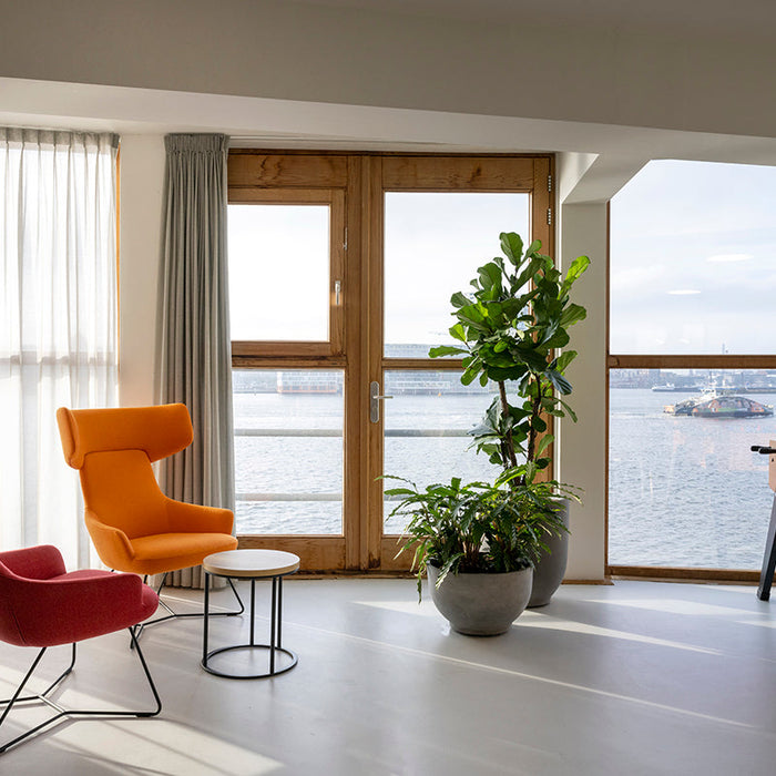 Moderne kantoorruimte met design kantoormeubels, lounge stoelen, planten en tafelvoetbal, uitzicht op het water