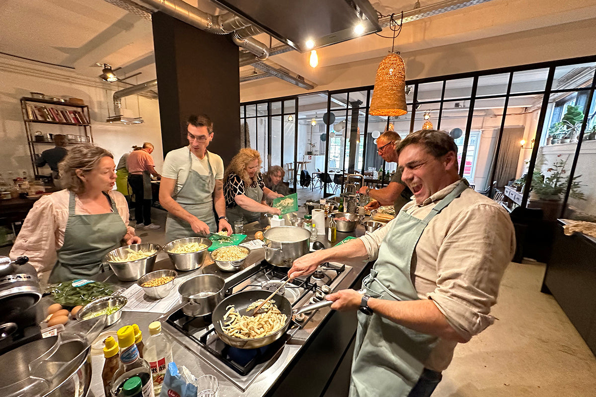 Teamuitje koken in moderne keuken, groep collega's bereidt samen eten, gezellige sfeer