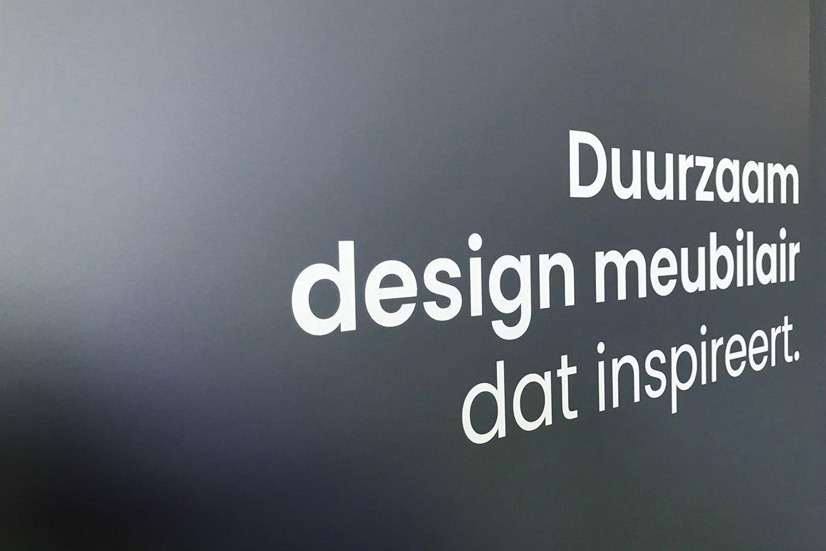 Grijze muur met witte tekst: Duurzaam design meubilair dat inspireert, kantoormeubels.online