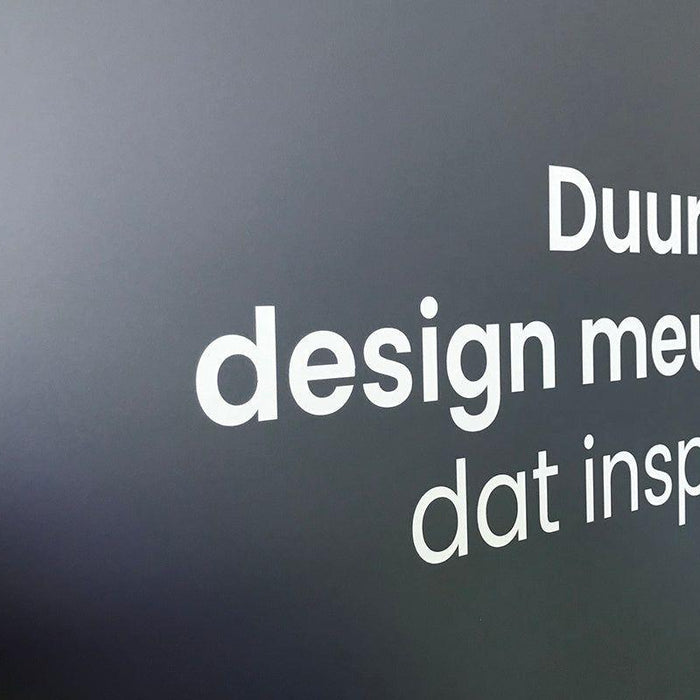 Grijze muur met witte tekst: Duurzaam design meubilair dat inspireert, kantoormeubels.online