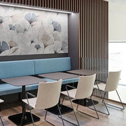 Moderne kantoor zithoek met blauwe bank, design stoelen en akoestisch wandpaneel