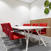 Moderne vergaderruimte met witte Bridge vergadertafel, rode Alfa stoelen met hoge rug en groene muurdecoratie, moswand, kantoormeubilair