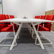 Moderne vergaderruimte met witte Bridge vergadertafel en rode design vergaderstoelen op grijs tapijt