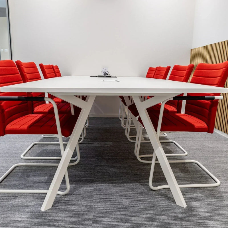 Moderne vergaderruimte met witte Bridge vergadertafel en rode design vergaderstoelen op grijs tapijt