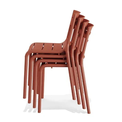 Vier gestapelde terracotta design stoelen, ideaal voor kantoor of vergaderruimte