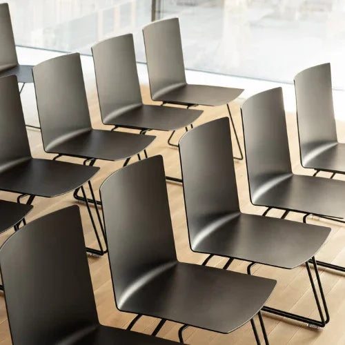 Design kantoormeubilair: moderne zwarte zaalstoelen in congresruimte met houten vloer