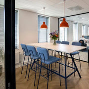 kantoorinrichting met blauwe Forza barkrukken, hoge Bridge tafel met zwart frame en oranje hanglampen