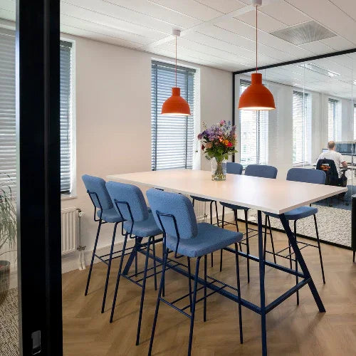 kantoorinrichting met blauwe Forza barkrukken, hoge Bridge tafel met zwart frame en oranje hanglampen