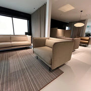 Moderne kantoorruimte met design zitbanken, akoestische panelen en vloerkleed bij daglicht.