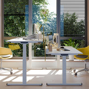 Modern zit-sta bureau met gele bureaustoelen en groene planten, ideaal voor kantoorinrichting.