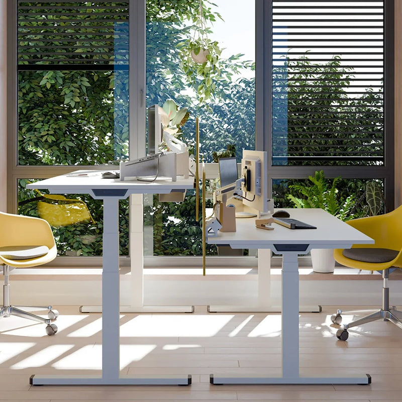 Modern zit-sta bureau met gele bureaustoelen en groene planten, ideaal voor kantoorinrichting.