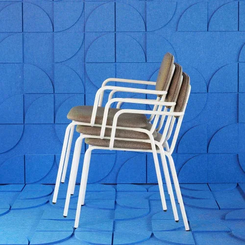 Stapelbare design armstoelen met witte poten voor kantoor, tegen blauwe wand.