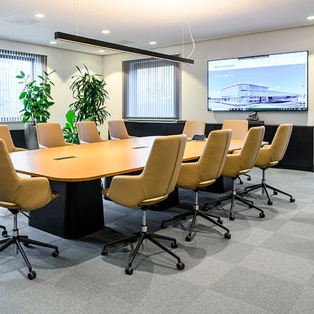 Moderne vergaderruimte met design vergadertafel, comfortabele bureaustoelen en grote monitor.