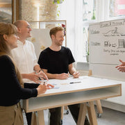 Teamoverleg bij sta-bureau met whiteboard, modern kantoormeubilair, inspirerende werkplek