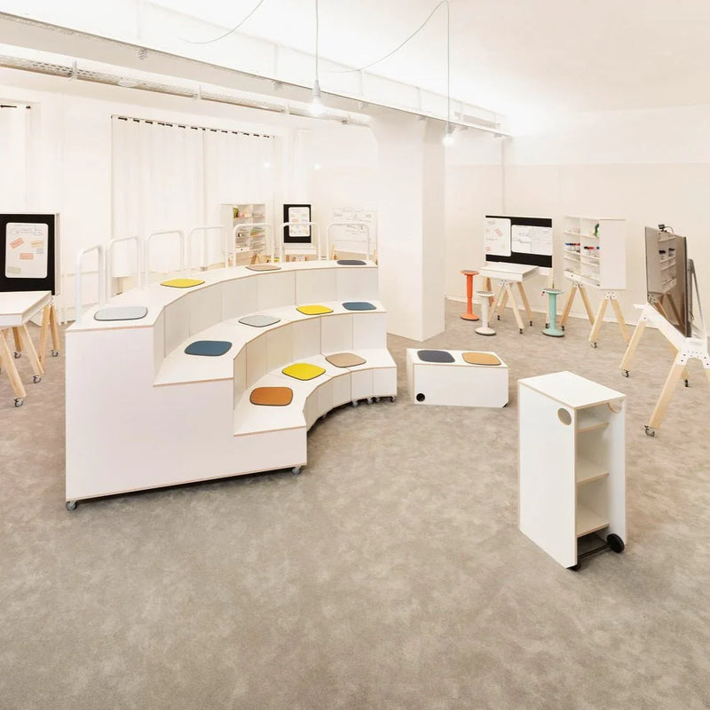 Moderne kantoormeubels met witte modulaire zittribune en kleurrijke zitkussens in lichte werkruimte