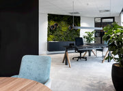 Modern design kantoorbureau met groene moswand, planten en ergonomische bureaustoel