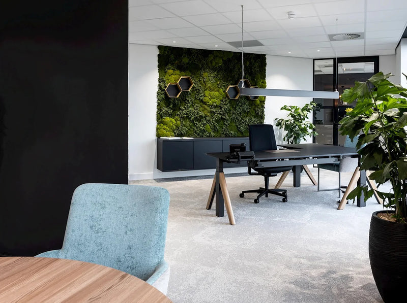 Modern design kantoorbureau met groene moswand, planten en ergonomische bureaustoel