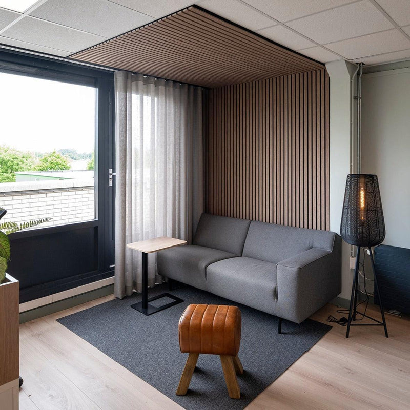 Moderne kantoorhoek met grijze bank, akoestisch PET-vilt lattenwand en design kantoormeubilair.