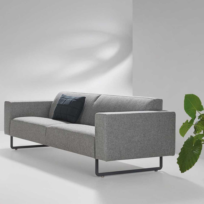 Grijze Artifort Mare bank in moderne kantoorruimte met zwarte kussen en groene plant