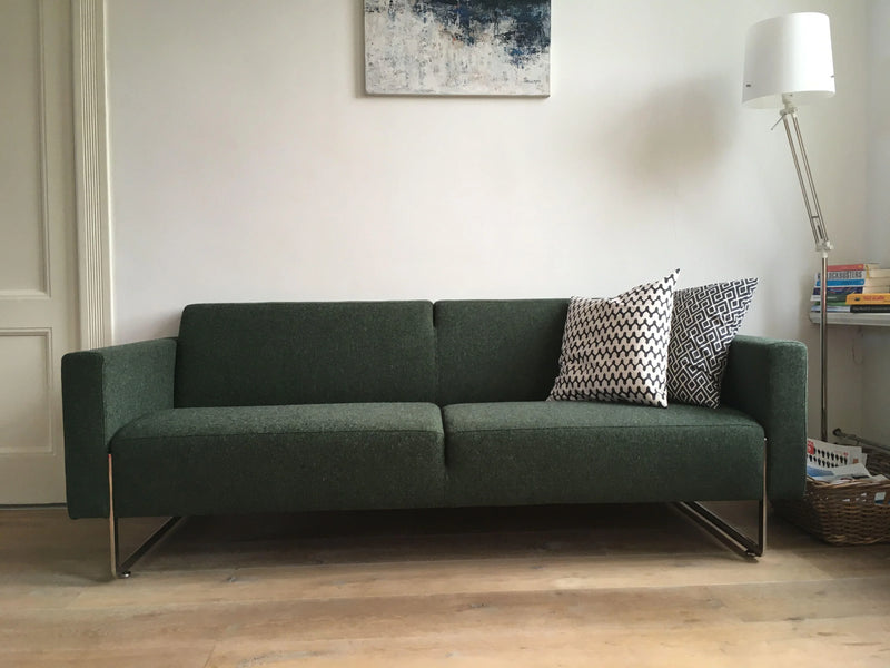 Groene Artifort Mare bank in een modern kantoorinterieur met kussens en vloerlamp