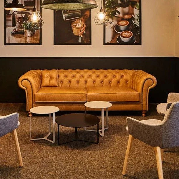 Chesterfield bank in kantoorruimte met moderne tafels en designstoelen, kantoormeubilair