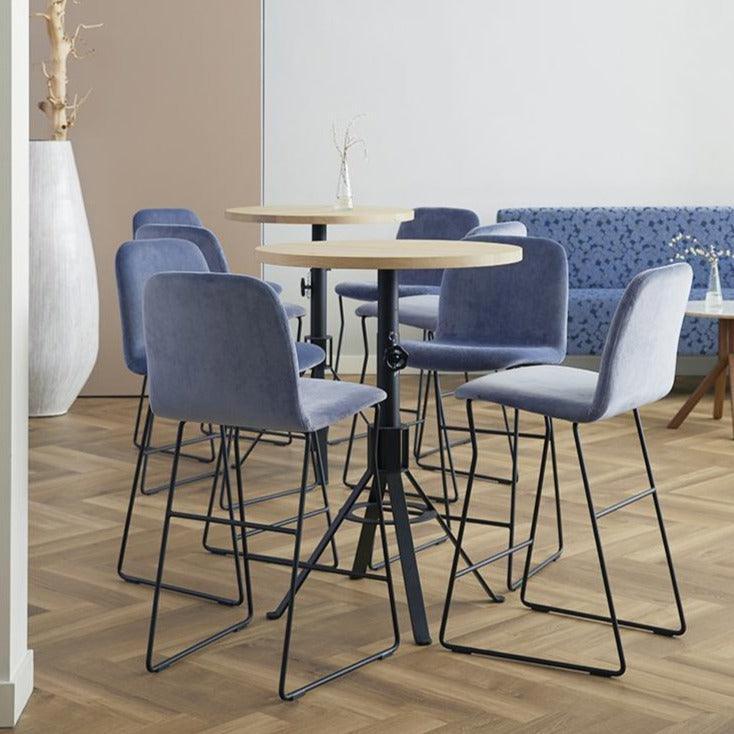 Moderne barkrukken en counterkrukken rond hoge tafels in een kantoorinrichting met designmeubilair