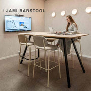 Design barkruk Jami in moderne kantoorruimte met hoge tafel en vrouw aan het werk