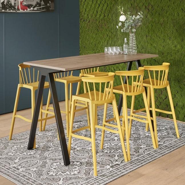 Moderne kantoorinrichting met houten tafel, gele barkrukken en groene moswand op vloerkleed
