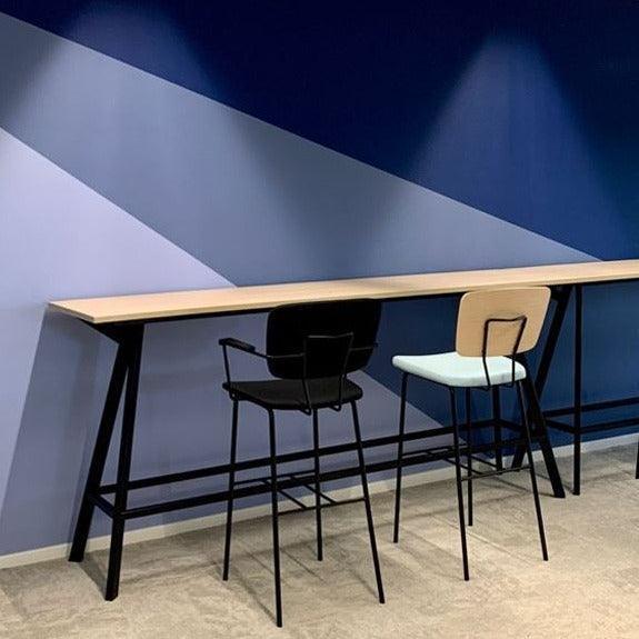 Moderne Bridge bartafel tegen blauwe wand, met twee hoge Forza stoelen in kantoorruimte, design kantoormeubilair