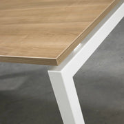 Detail van modern kantoor tafelblad met houtlook en wit stalen frame voor werkplek