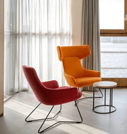 Moderne bijzettafel met zwart metalen frame naast design oranje en roze fauteuils bij raam, kantoormeubilair