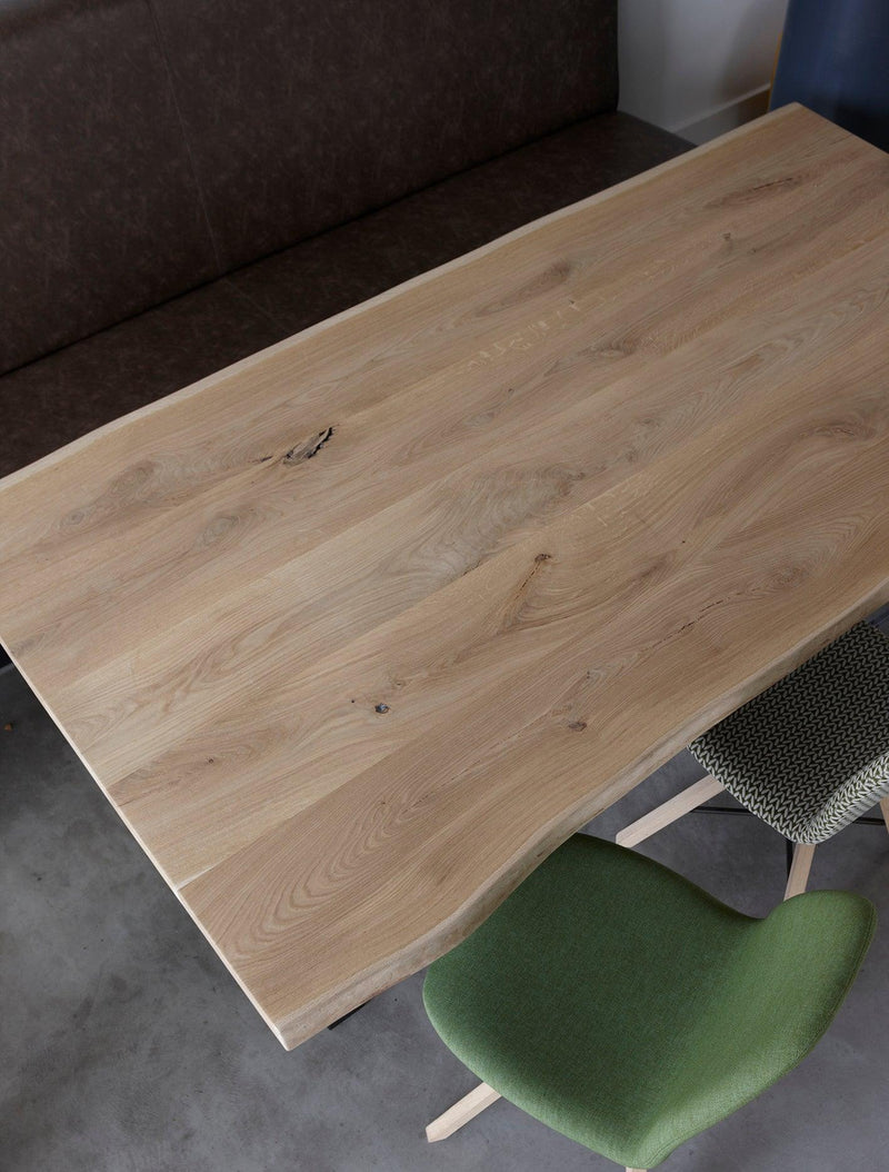 bovenaanzicht van boomstamtafel Bo met natuurlijke rand, groene stoel en treinbank in moderne kantine