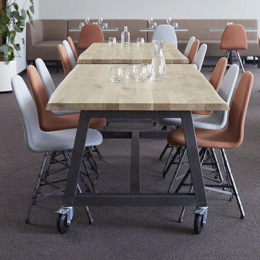 Boomstamtafel met stalen onderstel en design stoelen in moderne kantoorruimte