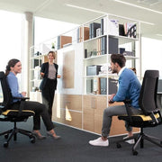 Moderne kantoorruimte met twee mensen op Interstuhl Joyce bureaustoelen en collega staand, design kantoormeubilair.